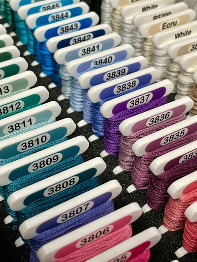 Premium DMC Acrylic cross stitch bobbins with thread wrapped on them in a foam insert. Made by Pip and Chip