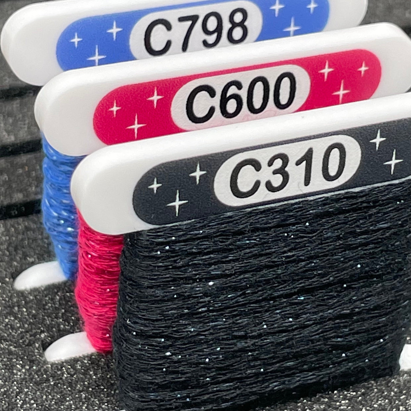 White DMC Etoile cross stitch acrylic bobbin with printed swatch by Pip and Chip
